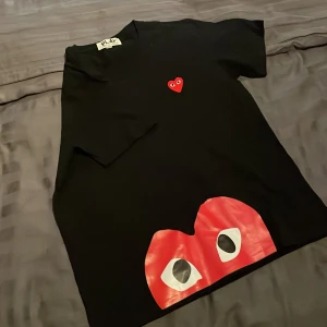 Comme des garçons t-shirt  - Snygg svart t-shirt från PLAY med ett ikoniskt rött hjärta med ögon på bröstet och ett större tryck nedtill. Perfekt för en stilren look. L men passar m 