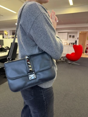  Valentino Garavani - Glamlock - Snygg svart axelväska från Valentino Garavani i skinn med kedjerem och nitar. Köpt ny på Mytheresa för ca. 14.000kr, mycket använd där av priset❣️Skriv för fler bilder. Kan gå ned i pris vid snabb affär.