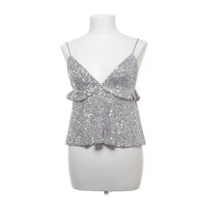 Glittrig silver linnetopp Subdued - Original pris 400kr Säljer en glittrig silverfärgad linnetopp från Subdued i storlek M. Toppen har smala axelband, v-ringad front och volangdetalj under bysten. Perfekt för att sticka ut med paljetter och en croppad passform. Superfin till jeans eller kjol! Använd två gånger