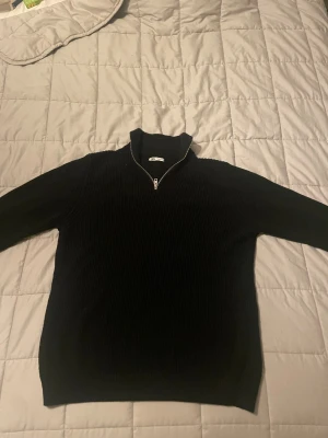Svart ribbad half zip tröja från Zara - Svart stickad tröja från Zara i storlek M med ribbad struktur och half zip-dragkedja vid halsen. Tröjan har långärmad design och en hög krage som ger en chill och stilren vibe. Perfekt för dig som gillar enkel men snygg look. 