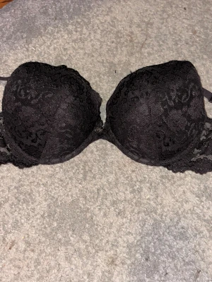 Svart spetsmönstrad bh 85C - Svart bh med snygg spetsmönstrad framsida och slät insida. Kuporna är formade och ger bra stöd, medan spetsen på sidorna ger en extra touch.  Har använt den max två gånger. Men är så klart nytvättad 