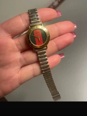 Vintage klocka  -  klocka från Gucci med metallarmband silver stål  och guldfärgad boett, samt röd och grön urtavla.  Vintage klocka från mormors tid. 