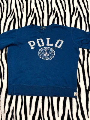 Ralph Lauren - Blå sweatshirt från Polo Ralph Lauren. Det finns 1 defekt det vi ser sista bilden ett litet hål i ryggen där nere. Storlek är i kids L (14-16) vilket blir XS i vuxen. Hör av dig vid minsta fundering 😀 