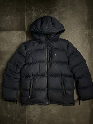 Ralph lauren pufferjacka  - Ralph lauren pufferjacket i använt skick, de finns skador och den är även smutsig, kolla alla bilder, finns lite fler skador så skriv för fler bilder, storlek L 14-16/ xs