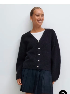 Blå stickad kofta med knappar - Mysig blå stickad kofta med v-ringning och silvriga knappar framtill. Koftan har långärmad passform och är perfekt att slänga över en t-shirt för en chill look. Enkel och stilren design som funkar till det mesta.