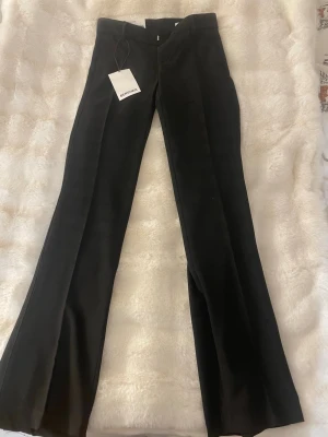 Svarta low rise slim byxor från Bershka - Snygga svarta byxor från Bershka i modellen low rise slim. Byxorna har en smal passform och låg midja, med klassisk rak design och  diskret dragkedja framtill. Perfekta för dig som gillar stilrena och moderna plagg. Säljer då de va för små och fick de i julklapp så gick inte att lämna tillbaka