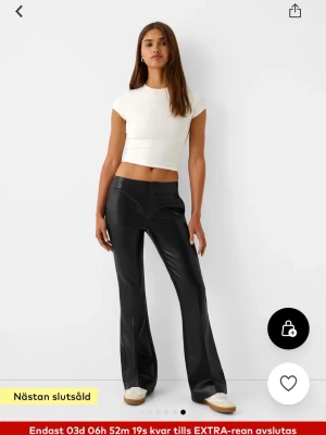 Svarta bootcut byxor i skinnimitation - ENDAST ANVÄNDA 1 GÅNG! helt i nyskick!! även slutsåld i S. Snygga svarta byxor i skinnimitation med låg midja och bootcut-ben. Byxorna har en clean look utan synliga knappar eller dragkedja framtill och har fickdetaljer bak. Perfekta för en trendig och edgy stil.