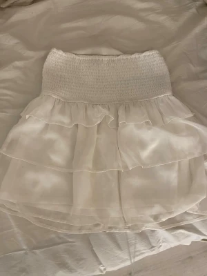 Vit volangkjol från Bikbok - Supersöt vit kortkjol från Bikbok i storlek S. Materialet känns lätt och luftigt. I mycket bra skick. Priset kan diskuteras.