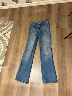 Blå low waist bootcut jeans  - Bootcut jeans från Lager 157 i klassisk blå tvätt med lätt slitning. Modellen har fem fickor, knapp och dragkedja fram samt läderpatch bak i midjan. Jeansen är tillverkade i bomull och har en snygg bootcut-passform som ger en schysst siluett.
