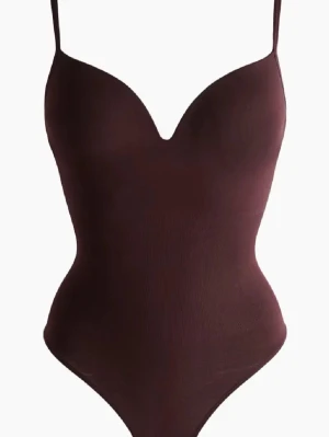 Populär H&M Body - Säljer denna fina body från h&m i vinröd/lilaröd. Väldigt fin färg och sitter bekvämt. Knappt använd och har inga synliga defekter💕pris kan diskuteras