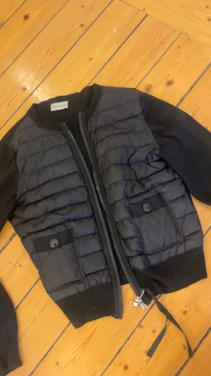Moncler cardigan dam  - Säljer en svart cardigan från Moncler!!🤗 Jackan har två fickor med knapp framtill och dragkedja. Perfekt för alla årstider!❤️❤️ köpte ifrån en annan tjej på Plick, men säljer då den satt dåligt på mig❤️ kan sälja för lägre pris vid snabb affär!❤️ skriv om du vill ha flera bilder osv 