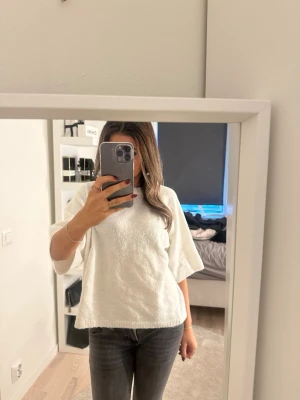 Vit stickad tröja från 157, XS - Mysig vit stickad tröja från 157 i storlek XS. Tröjan har en avslappnad passform med trekvartsärmar och ribbade kanter. Perfekt för lager-på-lager och enkel att matcha med jeans eller kjol.