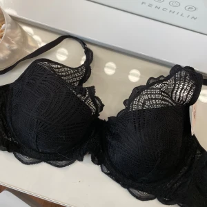 Svart spets-bh med vaddering 80C - Snygg svart bh med spetsdetaljer och lätt vaddering. Bh:n har fina mönstrade spetsar över kuporna och släta insidor för extra komfort. Aldrig använd och prislapp är kvar. Säljer för hälften av priset😍Går att spänna in 3 steg. Perfekt för dig som vill ha både stil och stöd.