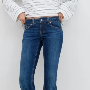 Blå lågmidjade bootcut jeans med fickdetaljer - Snygga blå jeans med bootcut passform och klassiska fickor med lock och knapp bak. Jeansen har låg midja och är gjorda i ett mjukt denimtyg med kontrastsömmar. Jeansen har inge defekter alls och är bara använda ett fåtal gånger. Inga slitningar nertill eller så💓skriv privat för fler bilder🙌🏻