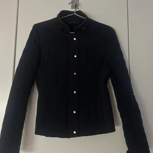 Svart quiltad jacka från Zara Woman - Snygg marinblå quiltad jacka från Zara Woman med guldfärgade knappar och ståkrage. Jackan har markerade sömmar och bruna detaljer längs kanterna. Perfekt för dig som gillar stilren och modern look med lite edge. Inhandlades för 699 kr - säljer för billigare!♥️