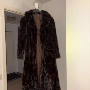 Brun pälskappa - Otroligt fin och lyxig lång kappa i äkta päls som passar perfekt nu till hösten och vintern. Varm, mjuk och elegant med en klassisk passform. I mycket fint skick, storlek xs/s🤍