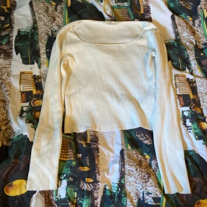 Vit ribbad långärmad topp - Säljer en vit ribbad långärmad topp med fyrkantig ringning. Toppen är croppad och har en slim passform som sitter snyggt på kroppen. Perfekt att styla med jeans eller kjol för en clean look.