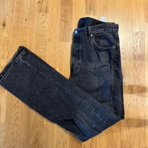 Levi's 501 svarta jeans W34 L34 - Klassiska svarta Levi's 501 jeans med rak passform och fem fickor. Jeansen har knappgylf och är tillverkade i robust denim av bomull. Perfekta för dig som gillar en tidlös och avslappnad stil. Om du har några funderingar är det bara att höra av sig🫡