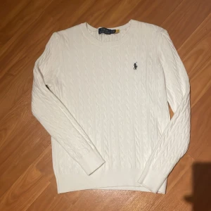 En vit Polo Ralph Lauren kabelstickad tröja - Vit kabelstickad tröja från Polo Ralph Lauren som är i storlek S.