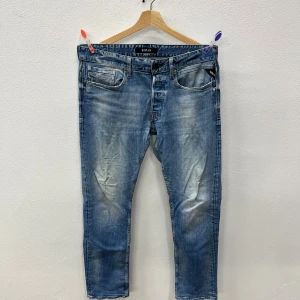 Replay jeans  - Säljer ett par snygga Replay jeans i ljusblå tvät. Jeansen har raka ben och normal passform, med slitningar och snyggt tvättad look. Perfekta för dig som gillar en avslappnad stil. Materialet är klassisk jeansbomull.