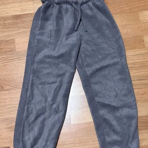 Grå fleecebyxor från Bodyzone KappAhl - Mysiga grå mjukisbyxor i fleece från Bodyzone by KappAhl. Byxorna har resår och snörning i midjan för skön passform och är perfekta för chill eller träning. Klassisk rak modell med mjukt material som känns skönt mot huden. Som nya väldigt bra skick 