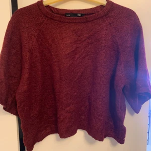 Vinröd stickad tröja från 157 - Mysig vinröd stickad tröja från 157 med kortare ärmar och avslappnad passform. Perfekt för lager-på-lager och chill höstkvällar. Rund halsringning och mjukt material som känns skönt mot huden.