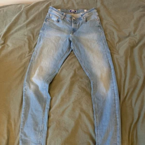 Ljusblå slim jeans från Jack & Jones - Säljer ett par ljusblå slim fit jeans från Jack & Jones. Klassisk femficksmodell med snygga detaljer på bakfickorna och en tydlig logga på bakre linningen. Jeansen har normal midja och är tillverkade i mjukt denimtyg för en bekväm känsla. 