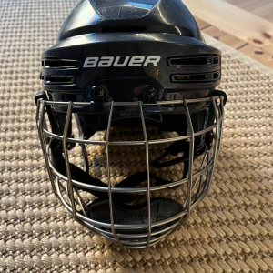 Bauer Reakt 75 S hockeyhjälm svart - Säljer en svart Bauer Reakt 75 S hockeyhjälm i storlek S (passar barn ca 8-10 år)  med galler och justerbart hakskydd. Hjälmen är i gott bruksskick. Ett föste till visiret har tappats, se bild. Lär finnas att beställa nytt. 