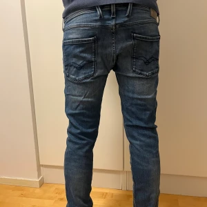 Blå Replay jeans - Säljer ett par blå Replay jeans med snygga detaljer och klassisk femficksdesign. Jeansen har smal passform, normal midja och är tillverkade i mjukt denimtyg. Perfekta för dig som gillar en modern och stilren look. Storlek 34/34