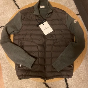 Grå Moncler Cardigan - Tjena👋 Säljer nu denna riktig feta Moncler Cardigan då den har blivit för liten📏 Jackan är i perfekt skick och har inga defekter🙅‍♂️ Jackan är i storlek S och passar mellan 170-176cm🙌 Kontakta gärna vid intresse är villig att gå ner i pris vid snabb affär💸