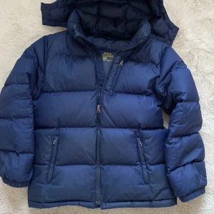 Blå dunjacka från Polo Ralph Lauren - Snygg jacka från RL, använd under en säsong, några defekter som på bilden men inget man märker när man andvänder den. Perfekt för kalla vinter dagar. XS/L i barn stl pris kan diskuteras