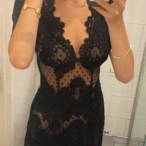 Svart spetsklänning Ida Sjöstedt - Supersnygg svart kort spetsklänning från Ida Sjöstedt med djup v-ringning och transparenta partier. Klänningen har korta ärmar, figurnära passform och vackra spetsdetaljer med prickigt mönster. Perfekt för dig som vill sticka ut med en elegant och trendig look. Använder inte så den är för pösig på mig. Originalpris 3400