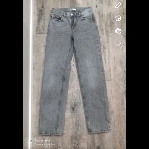Grå raka jeans från Gina tricot  - Säljer ett par grå jeans från Gina tricot med klassisk femficksdesign och raka ben. Jeansen har normal passform och är tillverkade i slitstarkt denimtyg. Perfekta för en avslappnad och stilren look.