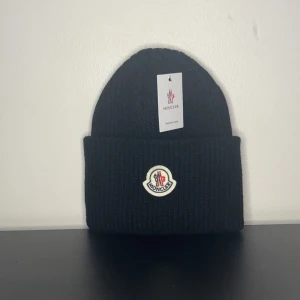 Moncler mössa - Säljer en fett mössa från Moncler som är perfekt nu till hösten och vinterns kalla dagar. Priset är inte hugget i sten🤗