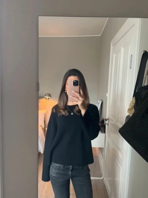 Other stories stickad tröja  - En svart stickad tröja med rund hals och långa ärmar. Tröjan har en loose passform och ribbade muddar vid ärmslut och nederkant. Perfekt för dig som gillar en enkel och stilren look.