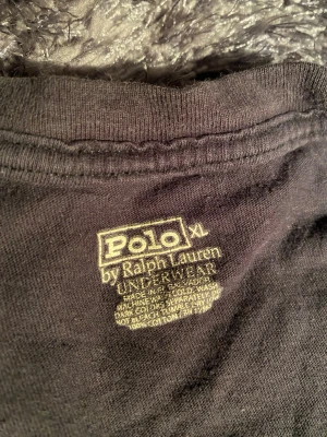 Svart v-ringad t-shirt Polo Ralph Lauren L - Svart v-ringad t-shirt från Polo Ralph Lauren i storlek XL men det är mer L tycker jag . Tillverkad i mjuk bomull och har en klassisk röd Polo-logga broderad längst ner på framsidan. T-shirten har korta ärmar och en clean, stilren look som funkar till jeans eller shorts.