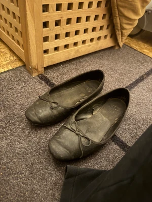 Svarta ballerinaskor med rosett - Säljer ett par svarta ballerinaskor med rund tå och en liten rosett framtill