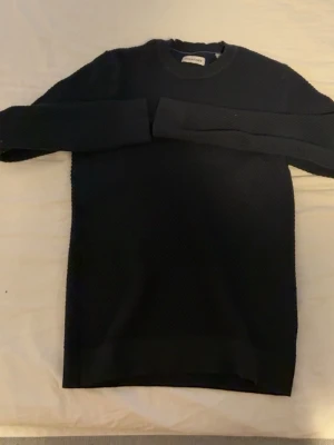 Svart stickad tröja från Jack & Jones - Säljer en svart stickad tröja från Jack & Jones i storlek M. Tröjan har rund hals, långärmade och är tillverkad i ett grovt stickat material som ger en snygg textur. Perfekt för dig som gillar stilrena och enkla plagg med lite struktur.