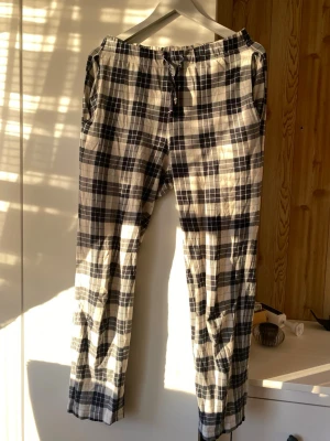 Blå och vita rutiga mjukisbyxor - Säljer ett par rutiga mjukisbyxor i mörkblått och vitt med snörning i midjan. Byxorna har avslappnad passform och är perfekta för chill dagar hemma. Materialet är mjukt och bekvämt, och de har praktiska sidofickor.
