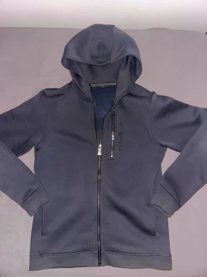 Sail racing zip, helt ny  - Skick:Helt ny.                                                              Storlek:170/S.                                                              Beskrivning: Helt ny sail racing zip i grå färg. Perfekt för alla årstider. Pris kan diskuteras