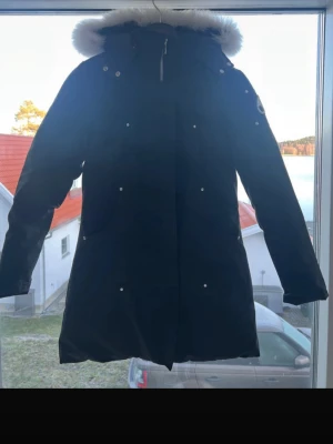 Moose knuckles jacka - Hej jag säljer en svart moose knuckles jacka som är som ny.  Den är sönder vid repet där man hänger upp jackan på(fråga om bild)  Annars är jackan helt ny använd 4 gånger max. Jackan är L men passar hundra procent bättte till M, jag som är s har jackan och den är lång men passar bra.