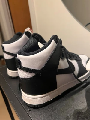 Nike Dunk High svart/vit sneakers - Nike Dunk High sneakers i svart och vitt med klassisk Swoosh på sidan. 