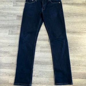 Levi's 511 mörkblå jeans - Mörkblå Levi's 511 jeans med klassisk femficksdesign och raka ben. Jeansen har en snygg, smal passform och är tillverkade i slitstarkt denim. Perfekta för dig som gillar en stilren look med ikoniska Levi's-detaljer och läderpatch bak. Storlek W33/L34