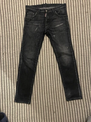 Svarta skinny jeans från Dsquared2 - Säljer ett par svarta skinny jeans från Dsquared2 i storlek 16Y. Jeansen har en cool tvätt med slitningar och detaljer, klassisk femficksdesign och Dsquared2-logga vid fickan. Materialet är bomull med lite elastan för extra komfort.