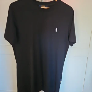 Svart t-shirt från Polo Ralph Lauren - Svart t-shirt från Polo Ralph Lauren, storlek M, säljer för att jag är lite för kort för den, endast testad, passar en som är 180cm+