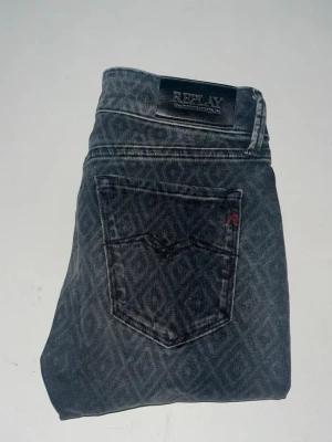 Replay jeans - Snygga Replay jeans i mörkgrått med coolt geometriskt mönster över hela byxan. Midja 32cm, längd 101cm. JAG SKICKAR EJ FLER BILDER NÄR JAG BÄR JEANSEN! för bättre inblick i passformen rekommenderar jag att googla på modellnamnet. För storleksguide kolla måtten noggrant då jeansen alltid kan vara uppsydda heller krympta och jag ej tar emot returer :) s5,1