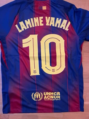 Barça fotbollströja 2025/26 Lamine Yamal #10 - Säljer en FC Barcelona matchtröja från 2025/26 med Lamine Yamal och nummer 10 på ryggen. Tröjan är randig i marinblått och rött med gula ränder. Materialet är polyester och har Dri-FIT teknologi. Pris kan diskuteras vid snabb affär och skickar fort! 