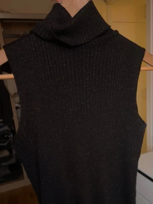 topp - svart glittrig topp med polokrage, står ingen storlek men passar mig xs/s. Köpt secondhand men fint skick