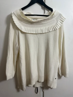 Vit stickad tröja Boomerang XL - Säljer en vit stickad tröja från Boomerang i storlek XL. Tröjan har en bred, ribbad krage och långa ärmar. Materialet är mjukt och grovstickat, perfekt för kyliga dagar. Snygg detalj med ribbad kant nedtill och vid kragen.