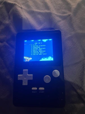 Denver GMP-320 Handhållen Spelkonsol - Retro handhållen spelkonsol från Denver med 200 inbyggda klassiska spel. Enkel att använda med tydliga knappar och volymkontroll. Drivs av 3x AA-batterier (inkluderade). Konsolen är i gott skick med mindre yttre slitage och en dekorativ klistermärke på baksidan.